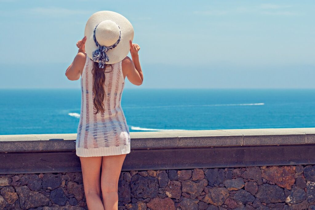 麦わら帽子をかぶって夏の海を見る女性